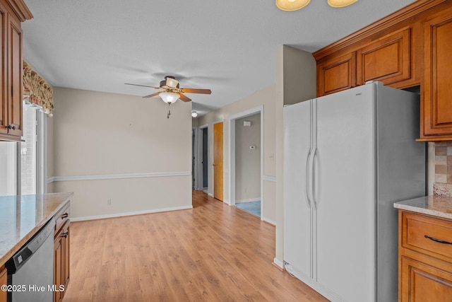 kitchen with light stone counters, dishwasher, white fridge, ceiling fan, and light hardwood / wood-style floors