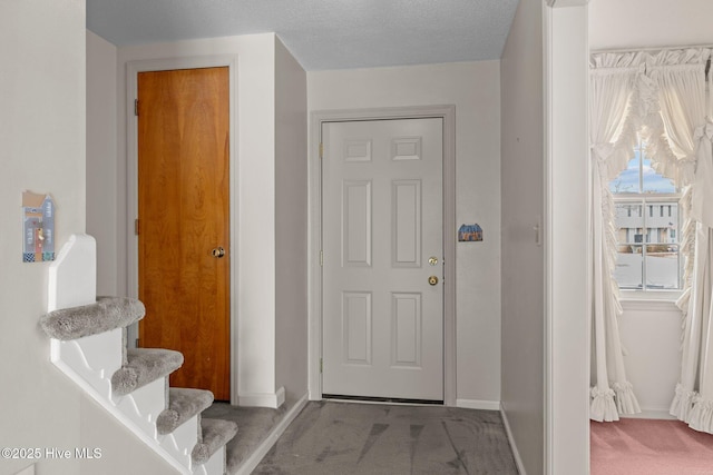 carpeted foyer entrance with a textured ceiling