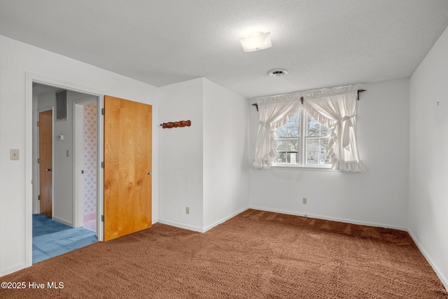 carpeted empty room with a textured ceiling