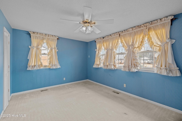 carpeted empty room featuring ceiling fan and a textured ceiling