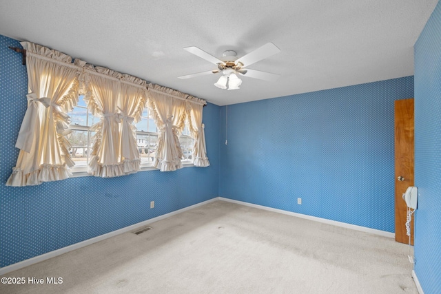 carpeted spare room featuring a textured ceiling and ceiling fan