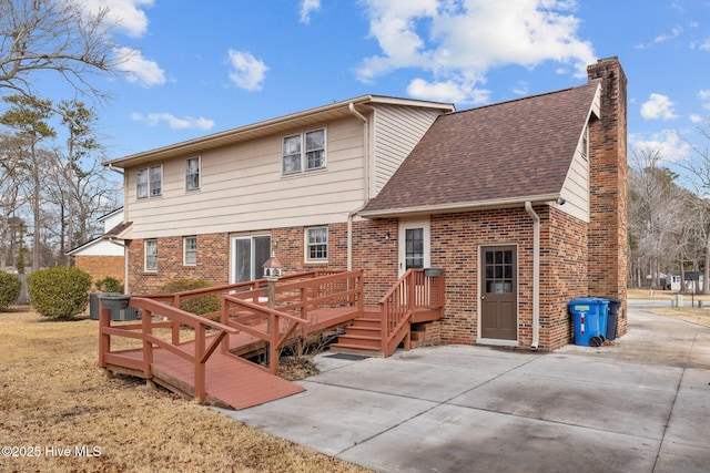 back of house with a wooden deck and a patio