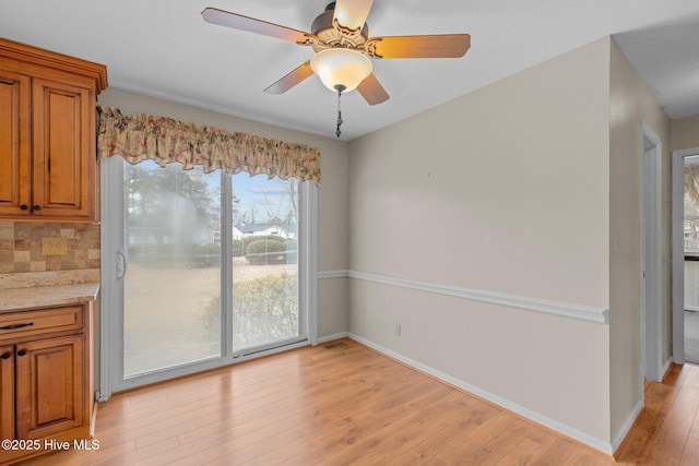 unfurnished dining area featuring ceiling fan and light wood-type flooring