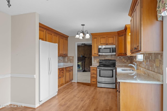 kitchen featuring sink, decorative light fixtures, a chandelier, light hardwood / wood-style flooring, and appliances with stainless steel finishes