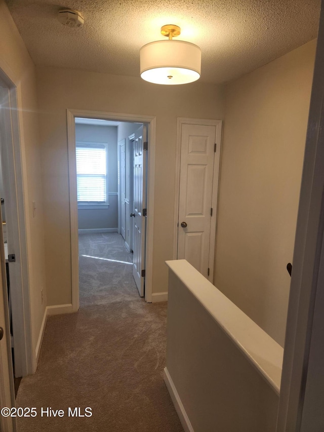 hallway featuring dark carpet and a textured ceiling