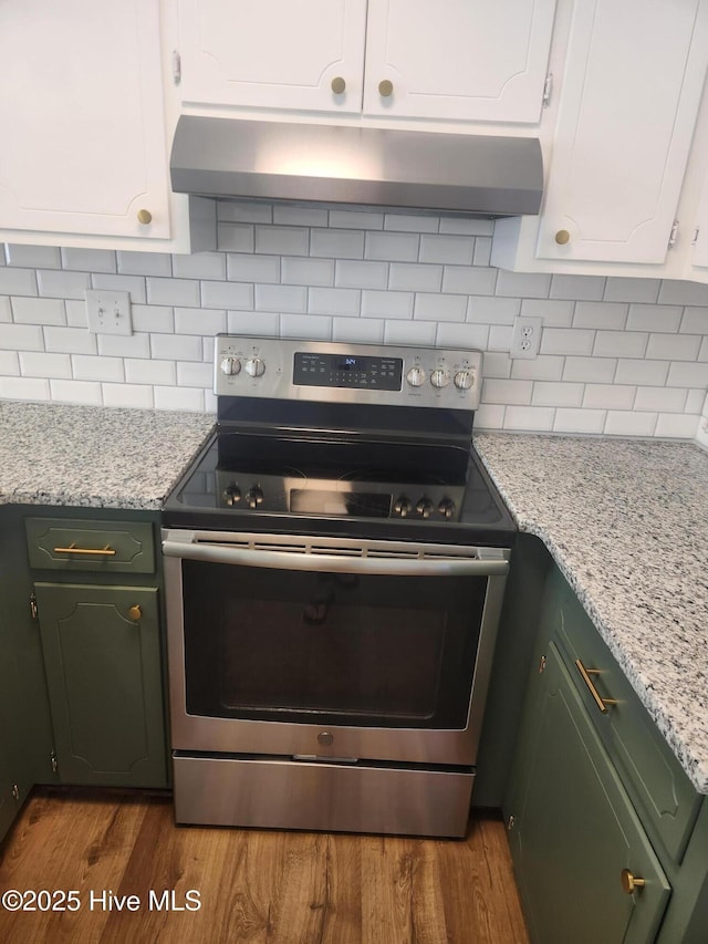 kitchen with electric stove, hardwood / wood-style flooring, tasteful backsplash, and white cabinets