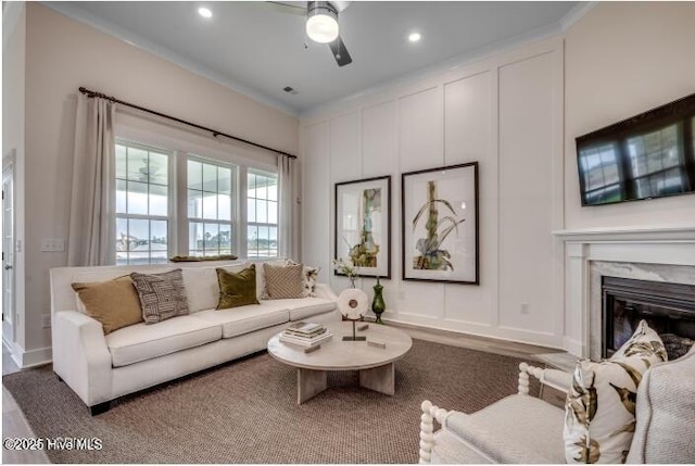 living room with a fireplace, ornamental molding, and ceiling fan