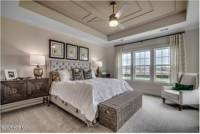 carpeted bedroom featuring a raised ceiling and ceiling fan