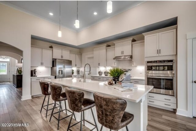 kitchen featuring appliances with stainless steel finishes, tasteful backsplash, an island with sink, sink, and a kitchen bar