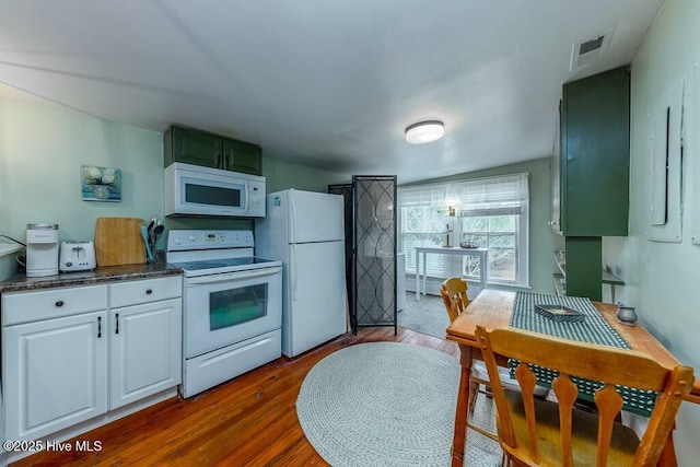 kitchen with white cabinetry, white appliances, and hardwood / wood-style flooring