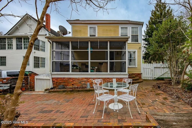 rear view of property with a sunroom and a patio area