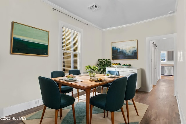 dining space with ornamental molding and wood-type flooring