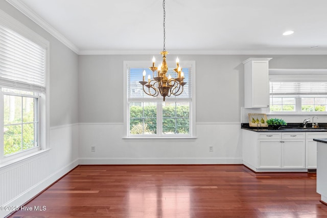 unfurnished dining area featuring dark hardwood / wood-style flooring, sink, a notable chandelier, and ornamental molding