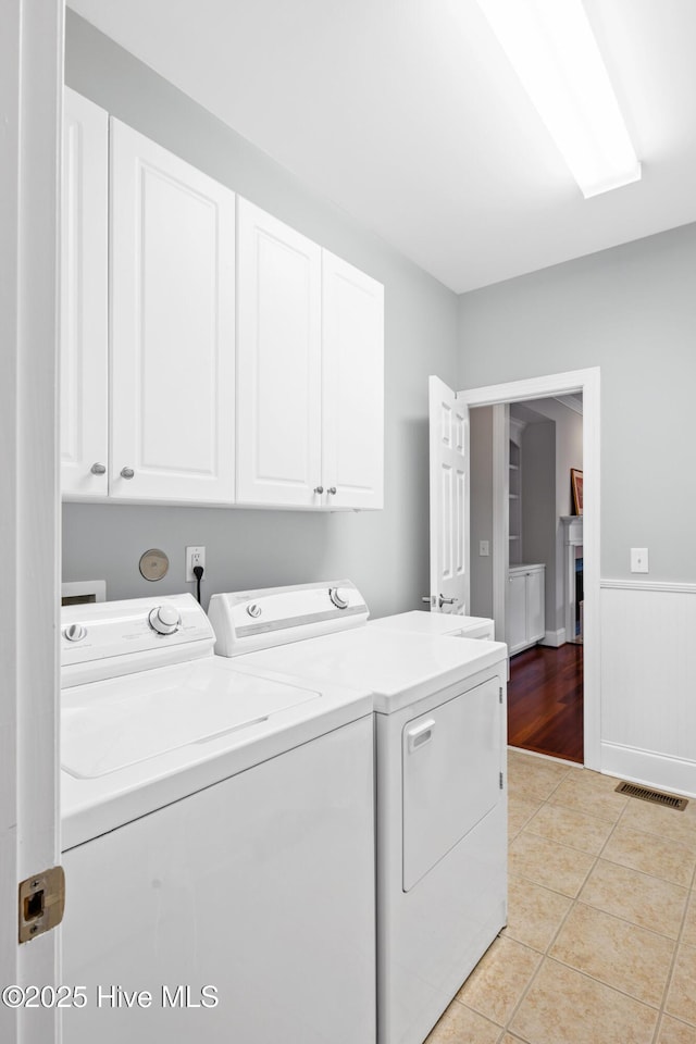 clothes washing area with light tile patterned flooring, cabinets, and washer and clothes dryer