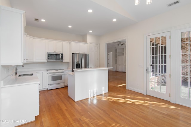 kitchen featuring stainless steel appliances, a kitchen island, sink, and white cabinets