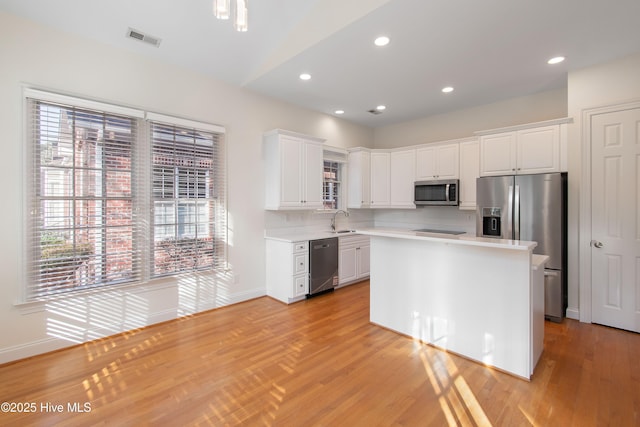 kitchen with stainless steel appliances, a center island, sink, and white cabinets