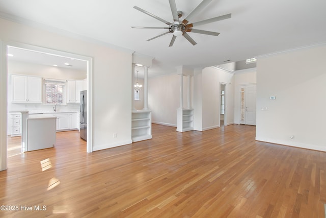 unfurnished living room featuring sink, light hardwood / wood-style flooring, ceiling fan, ornamental molding, and ornate columns