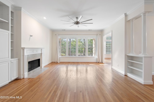 unfurnished living room featuring ceiling fan, a fireplace, light hardwood / wood-style flooring, and ornate columns