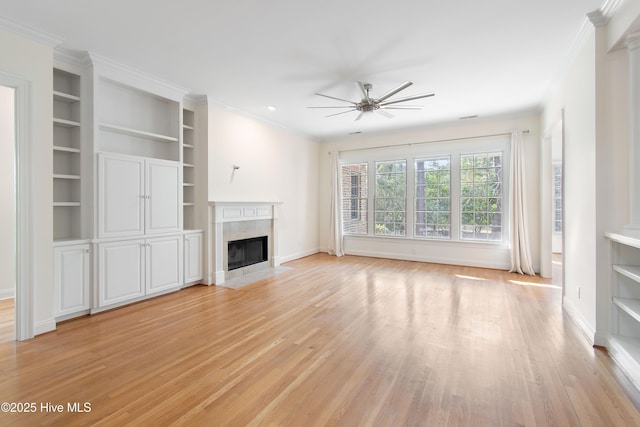 unfurnished living room featuring built in shelves, light hardwood / wood-style flooring, ornamental molding, ceiling fan, and a fireplace