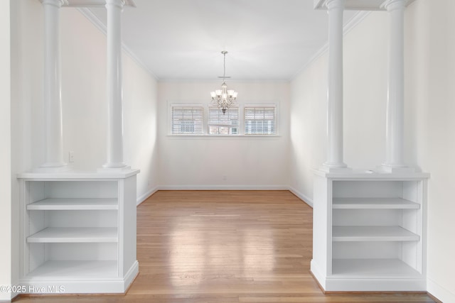 unfurnished dining area with built in shelves, ornate columns, ornamental molding, a notable chandelier, and hardwood / wood-style floors