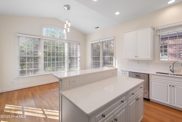 kitchen featuring sink, white cabinetry, decorative light fixtures, stainless steel dishwasher, and a kitchen island