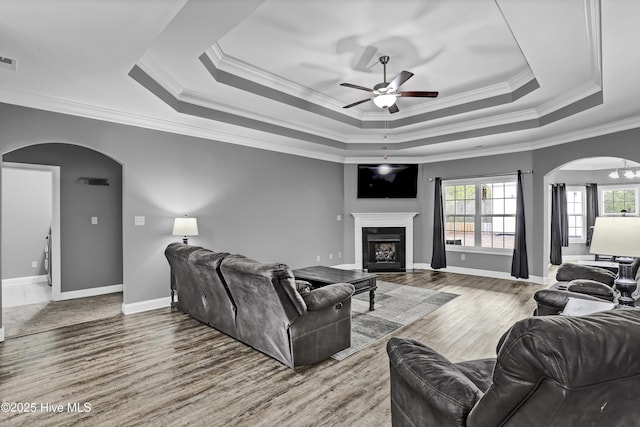 living room featuring hardwood / wood-style floors, a tray ceiling, and ornamental molding