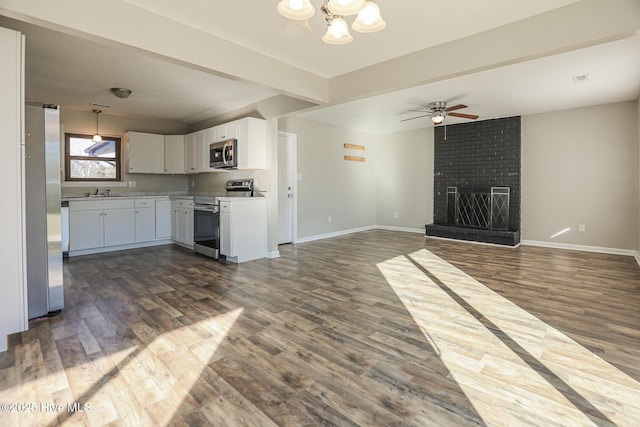 kitchen featuring dark hardwood / wood-style floors, a fireplace, white cabinetry, stainless steel appliances, and beam ceiling