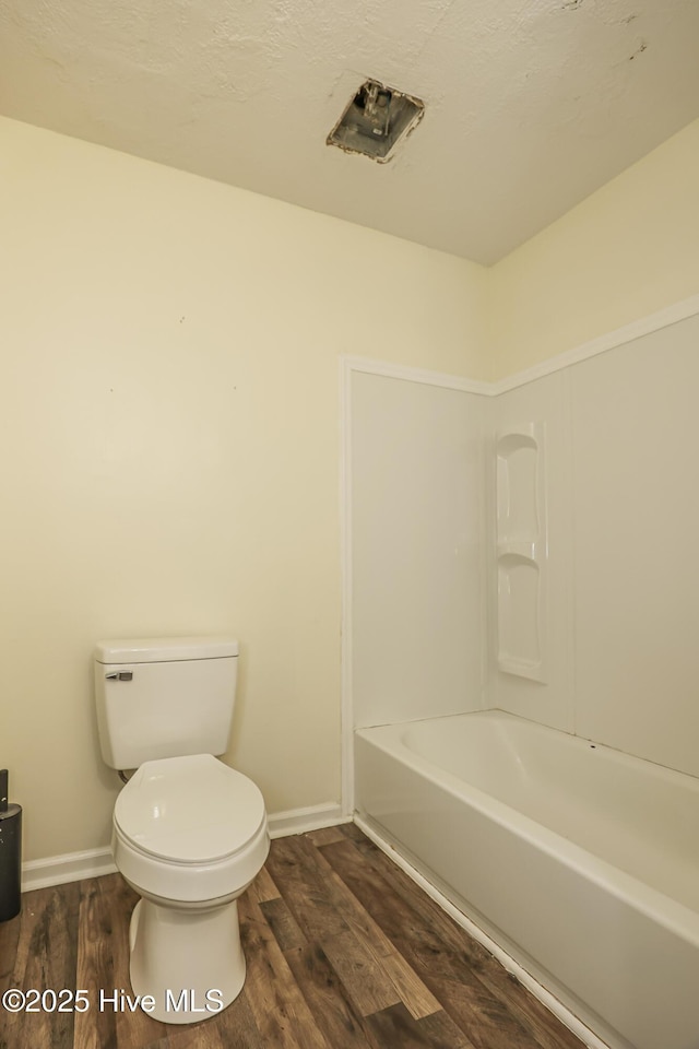 bathroom with toilet, hardwood / wood-style floors, and a textured ceiling