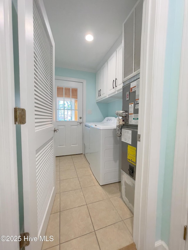 laundry room featuring cabinets, light tile patterned floors, and washing machine and clothes dryer