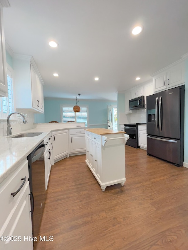 kitchen featuring sink, white cabinetry, decorative light fixtures, light hardwood / wood-style flooring, and black appliances