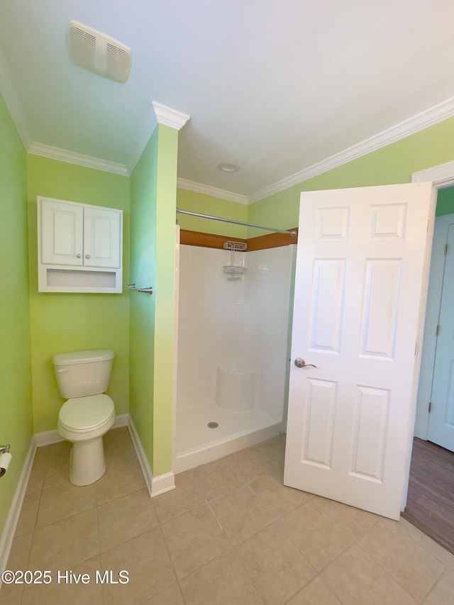 bathroom featuring tile patterned flooring, crown molding, toilet, and a shower