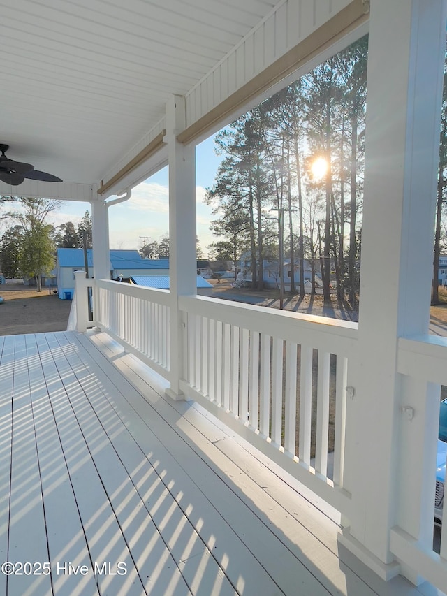 wooden terrace with a water view and ceiling fan