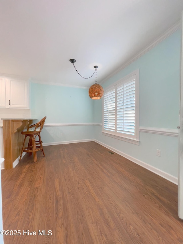 unfurnished dining area with ornamental molding and dark hardwood / wood-style flooring