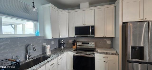 kitchen with appliances with stainless steel finishes, white cabinetry, sink, backsplash, and light stone counters