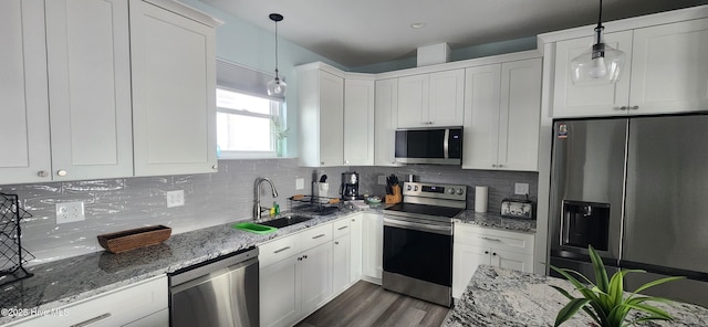 kitchen featuring appliances with stainless steel finishes, decorative light fixtures, sink, white cabinets, and light stone countertops