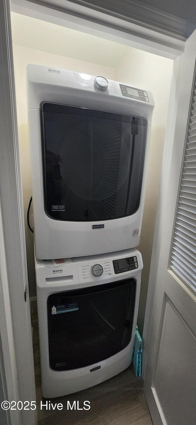 clothes washing area with hardwood / wood-style floors and stacked washer and clothes dryer