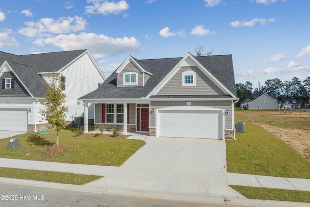 view of front of house featuring a porch, concrete driveway, central AC, stone siding, and a front lawn