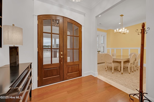 entrance foyer featuring ornamental molding, hardwood / wood-style floors, a chandelier, and french doors