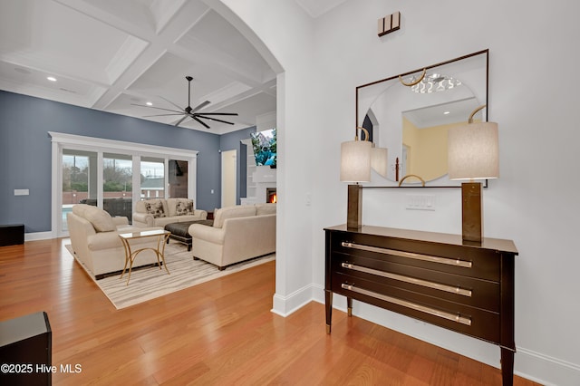 living room featuring coffered ceiling, beam ceiling, ceiling fan, and light wood-type flooring