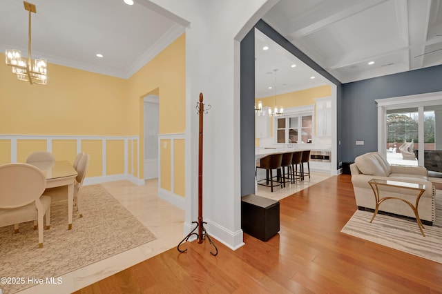 interior space with a notable chandelier, crown molding, light hardwood / wood-style floors, and beamed ceiling