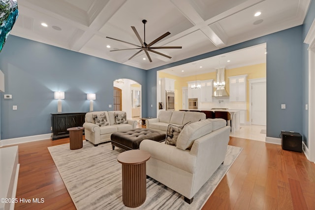 living room featuring beamed ceiling, ornamental molding, coffered ceiling, and light wood-type flooring