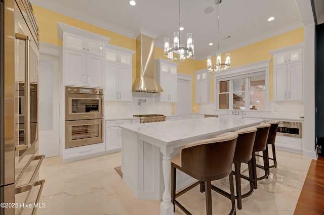 kitchen featuring stainless steel appliances, white cabinetry, a center island, and wall chimney exhaust hood