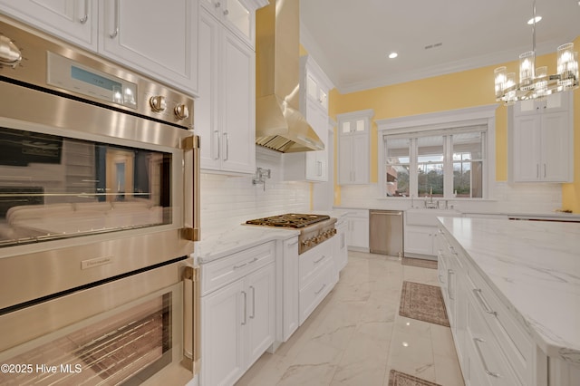 kitchen with white cabinetry, crown molding, wall chimney range hood, stainless steel appliances, and backsplash