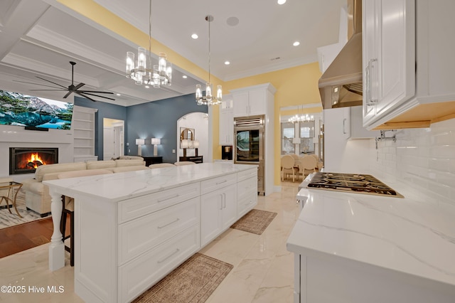 kitchen with pendant lighting, white cabinetry, a kitchen bar, a center island, and wall chimney range hood