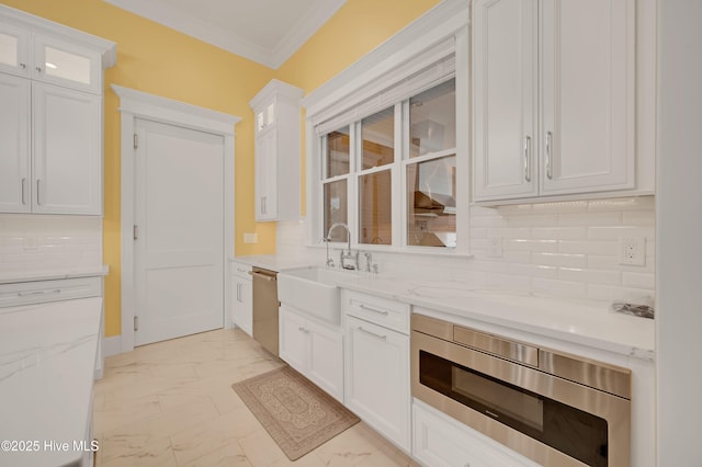 kitchen featuring appliances with stainless steel finishes, backsplash, white cabinets, light stone counters, and crown molding