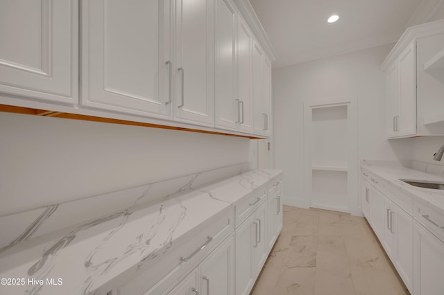 interior space featuring white cabinetry, sink, and light stone countertops