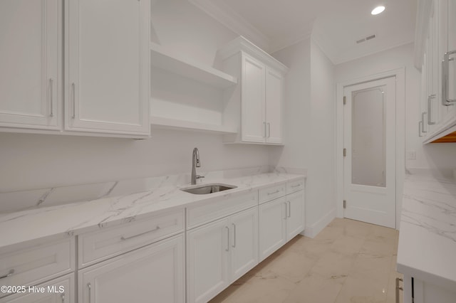 kitchen featuring light stone counters, sink, crown molding, and white cabinets