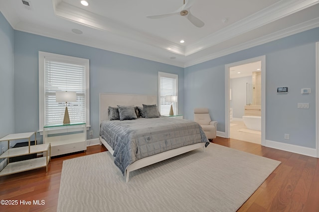 bedroom with ensuite bathroom, hardwood / wood-style floors, ceiling fan, a raised ceiling, and crown molding