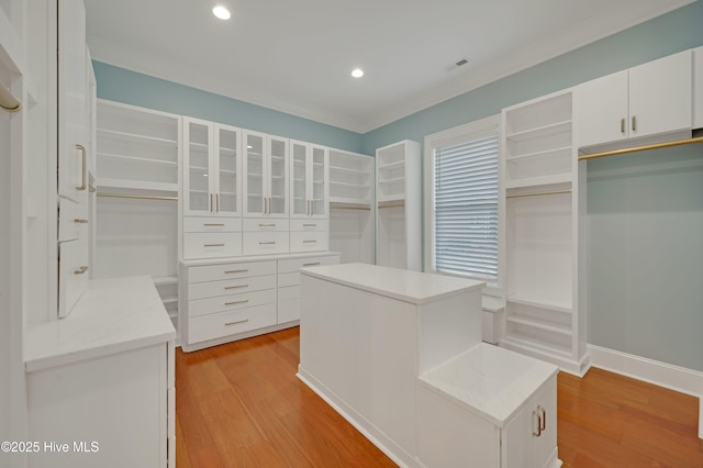 walk in closet with light hardwood / wood-style flooring