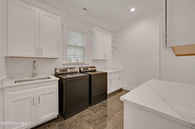 washroom featuring separate washer and dryer, sink, ornamental molding, and cabinets